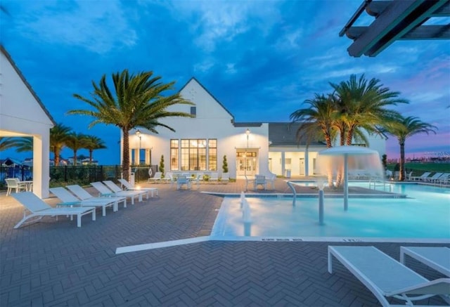 pool at dusk featuring a patio area and pool water feature