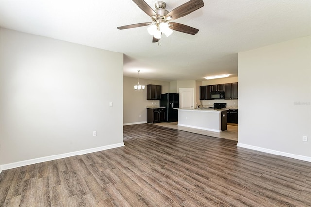 unfurnished living room with a textured ceiling, ceiling fan with notable chandelier, and dark hardwood / wood-style flooring