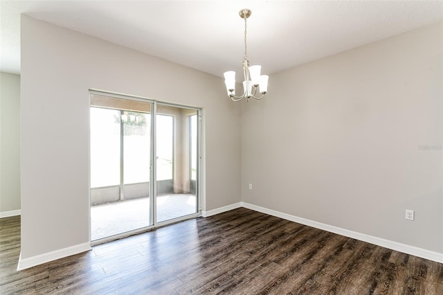 empty room with dark wood-type flooring and an inviting chandelier