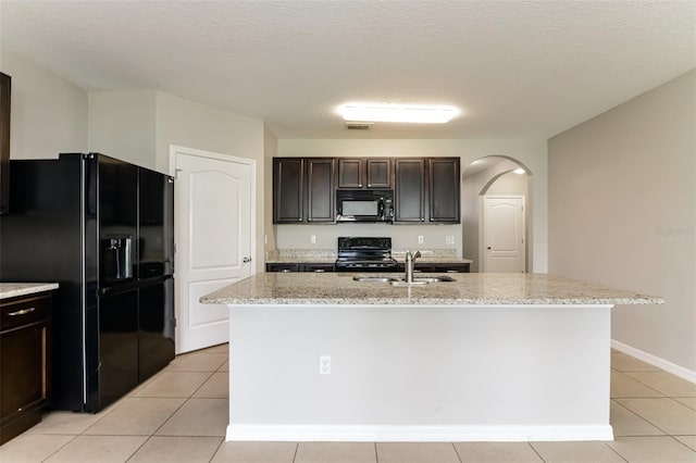 2036 Van Buren Loop, Auburndale, FL 33823 - kitchen with black appliances, arched walkways, light tile patterned floors, light stone countertops, and a kitchen island with sink