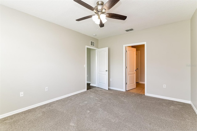 unfurnished bedroom featuring ceiling fan, light carpet, and a textured ceiling