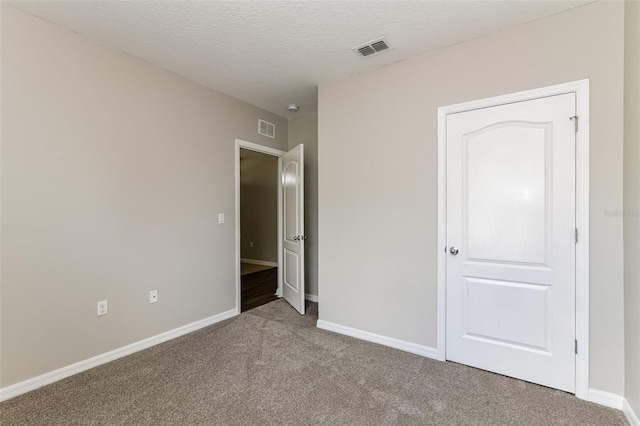 unfurnished bedroom featuring a textured ceiling and carpet