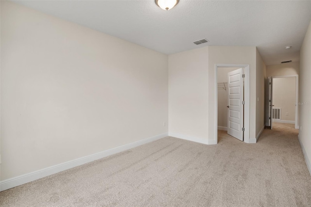 unfurnished bedroom with a closet, a spacious closet, and light colored carpet