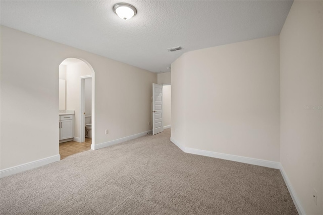 empty room featuring a textured ceiling and light colored carpet