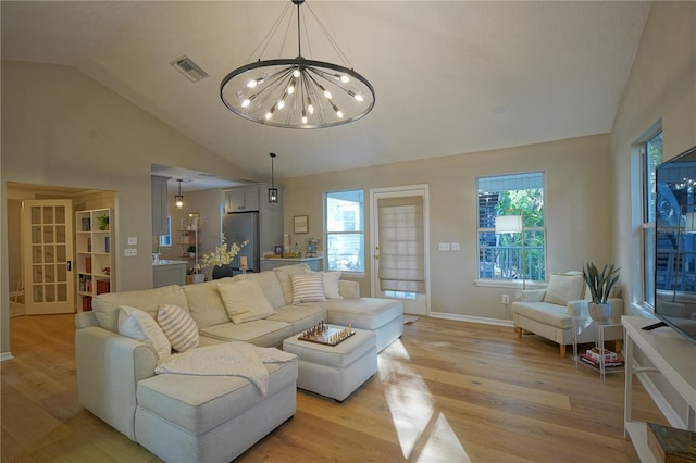 living room with an inviting chandelier, lofted ceiling, and light hardwood / wood-style floors