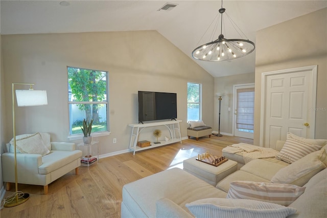 living room featuring an inviting chandelier, high vaulted ceiling, light hardwood / wood-style floors, and a healthy amount of sunlight