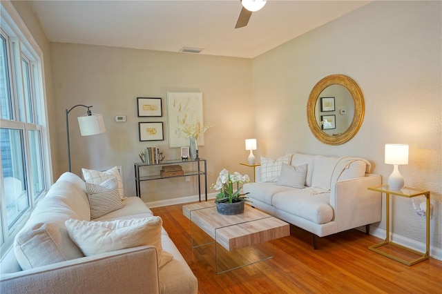 living room featuring ceiling fan, wood-type flooring, and a healthy amount of sunlight