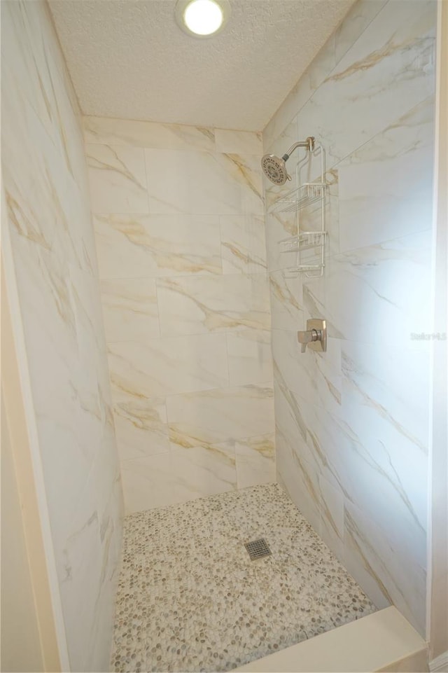 bathroom featuring a textured ceiling and a tile shower