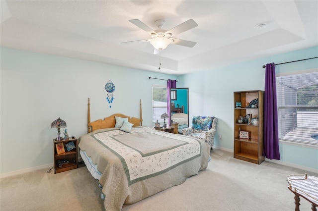 carpeted bedroom featuring a tray ceiling and ceiling fan