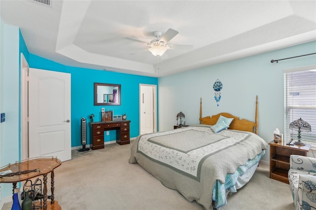 carpeted bedroom featuring a raised ceiling and ceiling fan