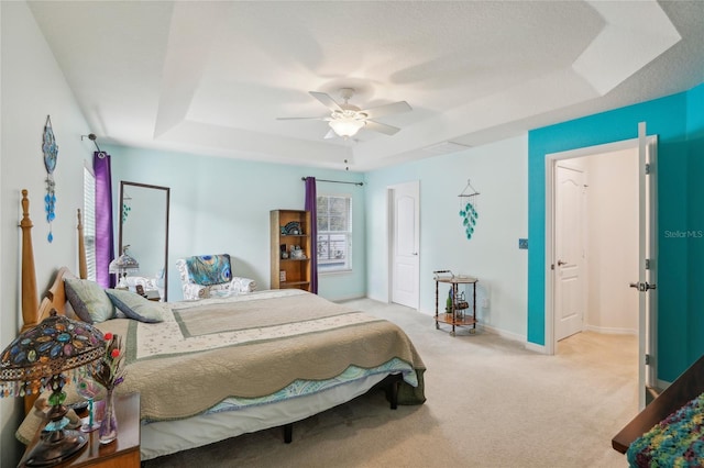 carpeted bedroom with ceiling fan and a raised ceiling