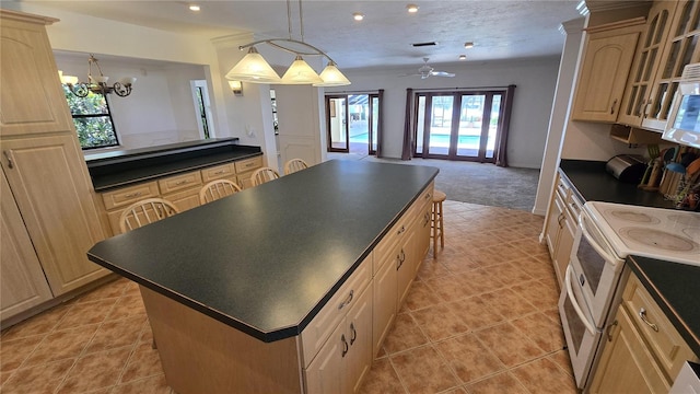 kitchen featuring a center island, light brown cabinets, pendant lighting, white appliances, and ceiling fan with notable chandelier