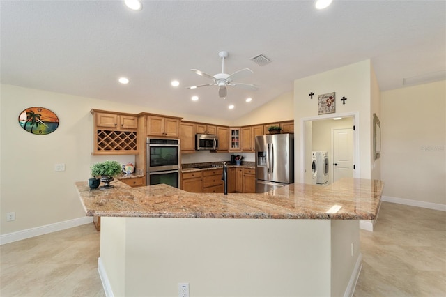 kitchen featuring kitchen peninsula, lofted ceiling, appliances with stainless steel finishes, separate washer and dryer, and light stone counters