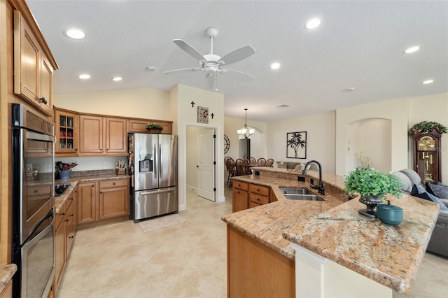 kitchen with hanging light fixtures, sink, vaulted ceiling, appliances with stainless steel finishes, and light stone counters