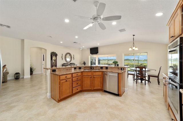 kitchen featuring lofted ceiling, stainless steel appliances, sink, pendant lighting, and ceiling fan with notable chandelier