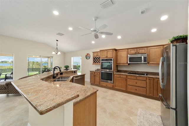 kitchen with sink, hanging light fixtures, stainless steel appliances, lofted ceiling, and a center island with sink