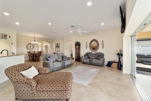 living room with light tile patterned floors, sink, and ceiling fan with notable chandelier