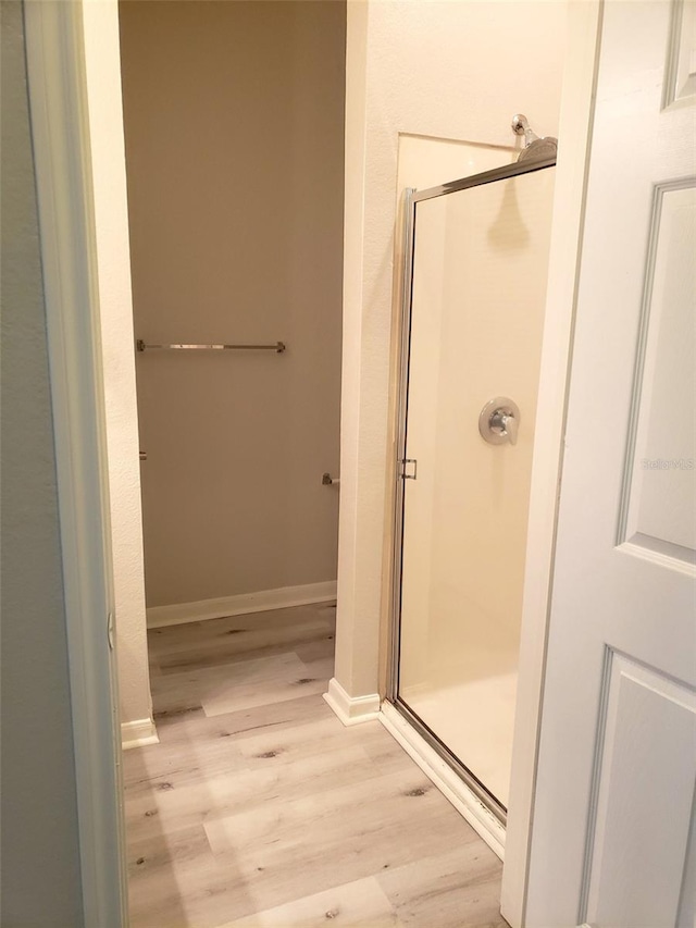 bathroom featuring a shower with shower door and hardwood / wood-style floors