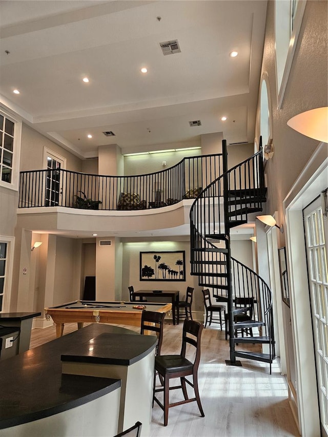 interior space with light hardwood / wood-style floors, a high ceiling, and pool table