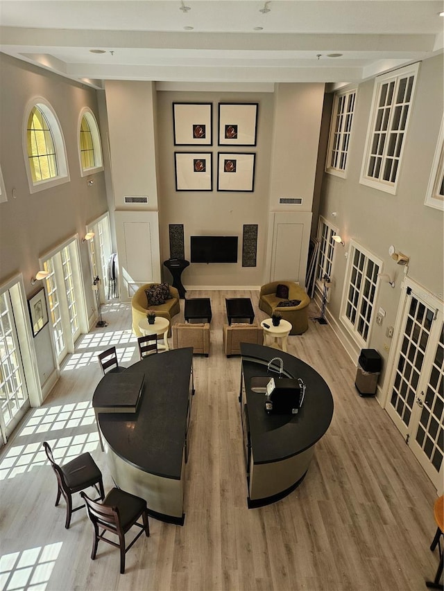 living room featuring light hardwood / wood-style floors, french doors, and a towering ceiling