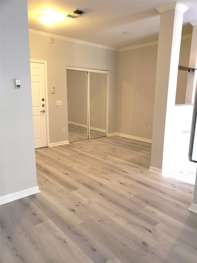 empty room with crown molding and light wood-type flooring