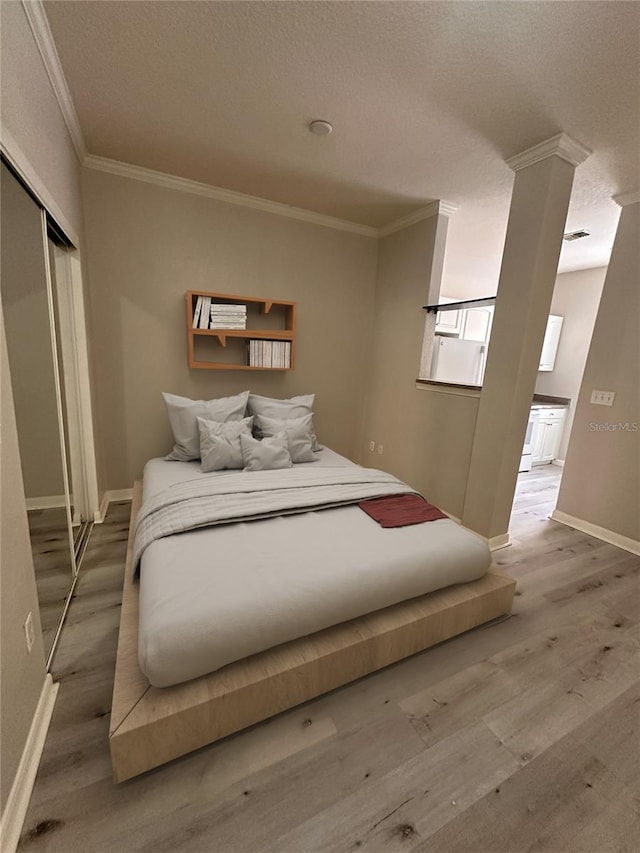 bedroom with ornamental molding, hardwood / wood-style floors, and a closet