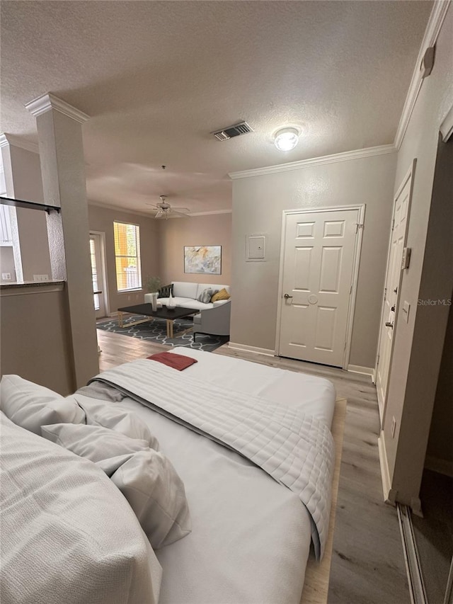 bedroom featuring crown molding, wood-type flooring, ceiling fan, and a textured ceiling