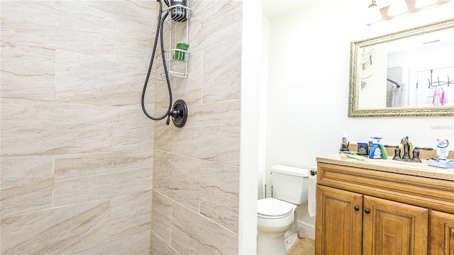 bathroom featuring vanity, tiled shower, and toilet