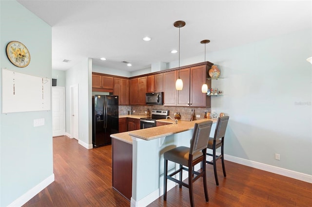 kitchen with dark hardwood / wood-style floors, a breakfast bar area, hanging light fixtures, kitchen peninsula, and black appliances