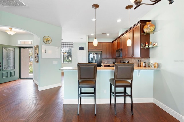 kitchen with decorative backsplash, dark hardwood / wood-style floors, kitchen peninsula, black appliances, and decorative light fixtures