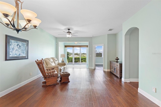 sitting room featuring dark wood-type flooring and ceiling fan with notable chandelier