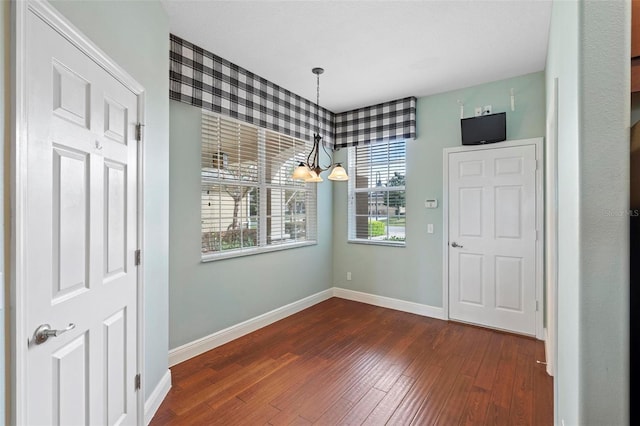 unfurnished dining area with a notable chandelier and dark hardwood / wood-style floors