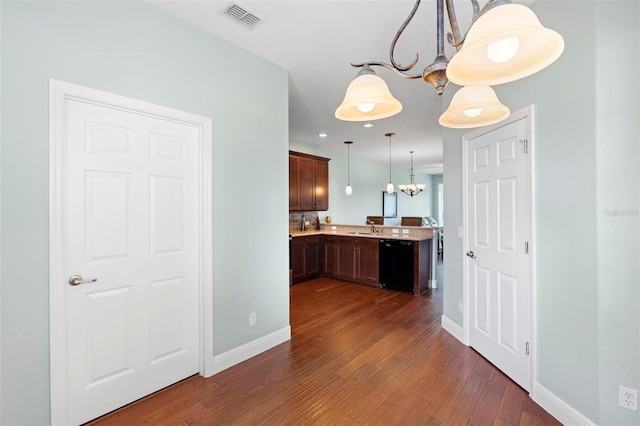 kitchen with dishwasher, dark wood-type flooring, sink, a notable chandelier, and pendant lighting