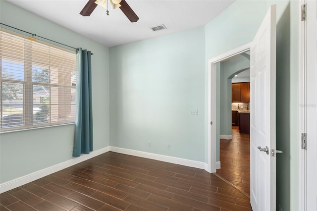 empty room featuring dark wood-type flooring and ceiling fan