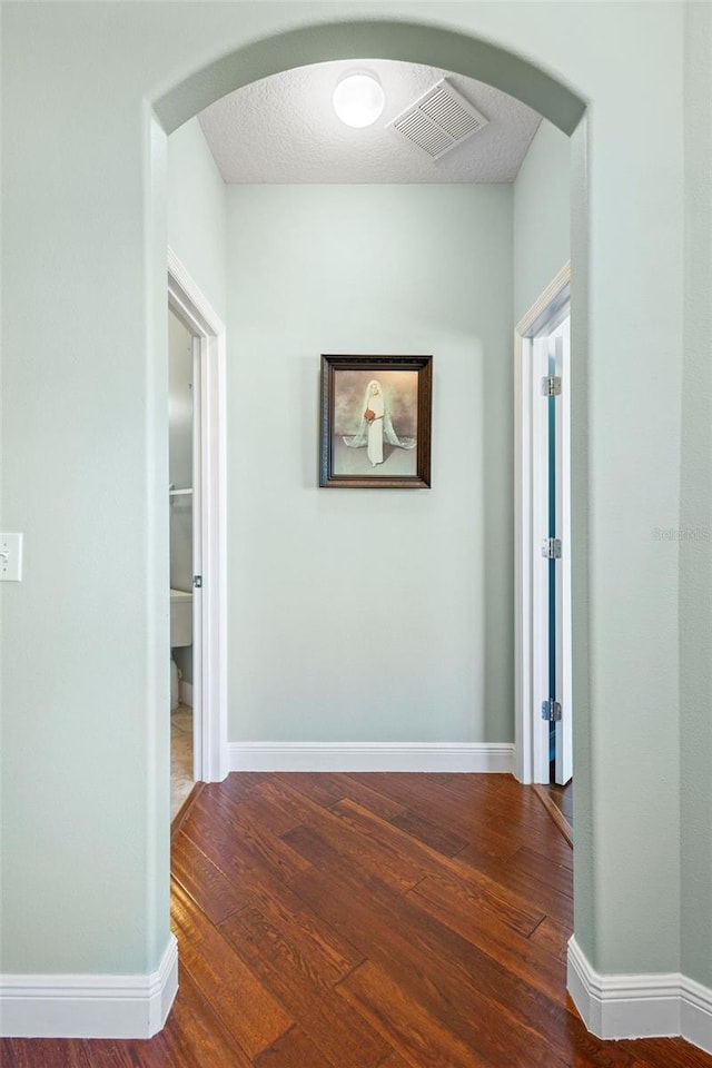 hallway featuring a textured ceiling and dark hardwood / wood-style floors