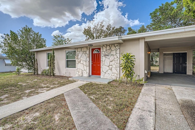 6445 Skyline Ct, Spring Hill, FL 34606 - view of front of house featuring stucco siding, driveway, stone siding, and a carport