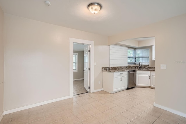 kitchen with dishwasher, dark stone counters, light tile patterned floors, and white cabinets