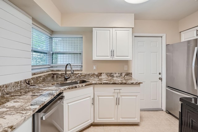 kitchen with sink, light tile patterned floors, white cabinetry, appliances with stainless steel finishes, and dark stone countertops