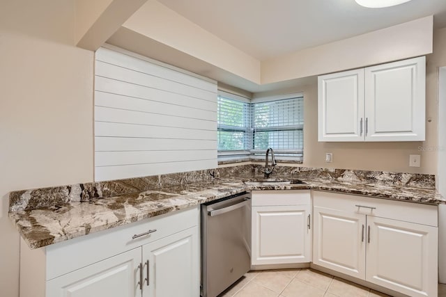 kitchen with dark stone countertops, white cabinetry, sink, and dishwasher