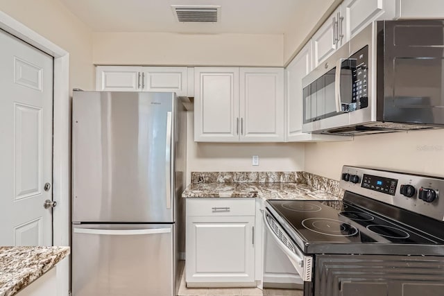 kitchen with light stone countertops, appliances with stainless steel finishes, and white cabinets