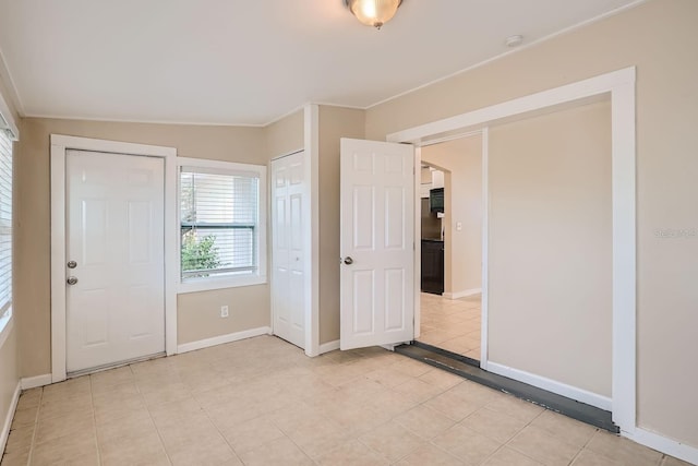 interior space featuring light tile patterned flooring, crown molding, and vaulted ceiling