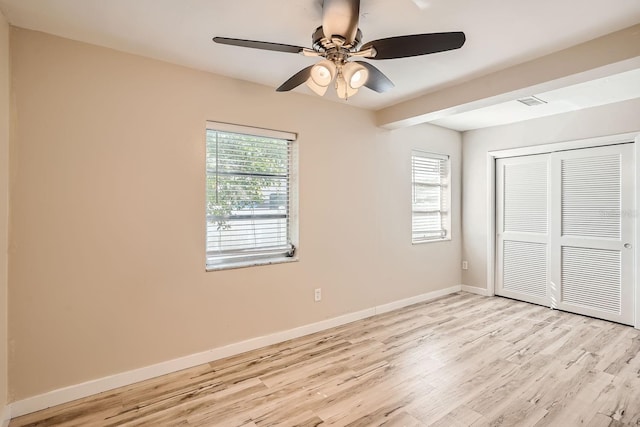 unfurnished bedroom with a closet, light wood-type flooring, multiple windows, and ceiling fan