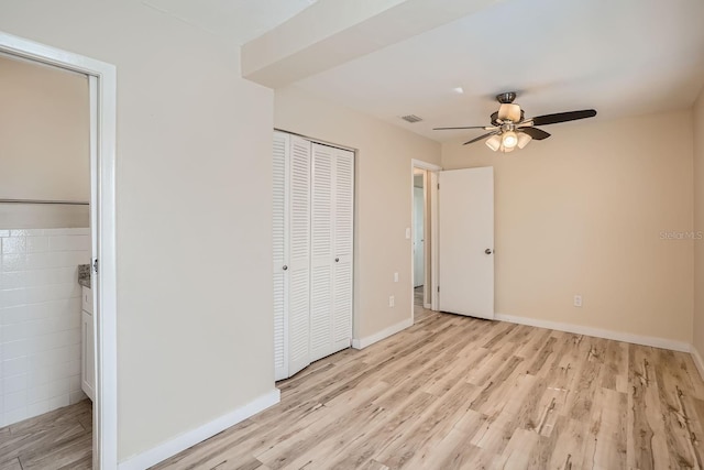 unfurnished bedroom with tile walls, light hardwood / wood-style floors, and ceiling fan