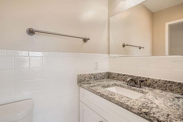 bathroom featuring toilet, vanity, and tile walls