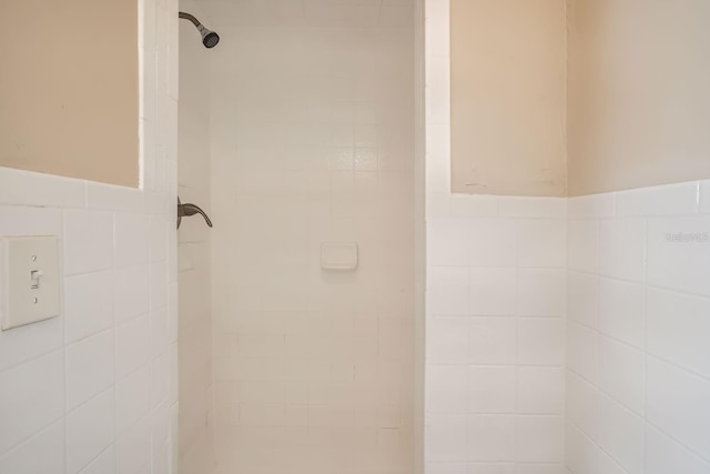 bathroom with tiled shower and tile walls