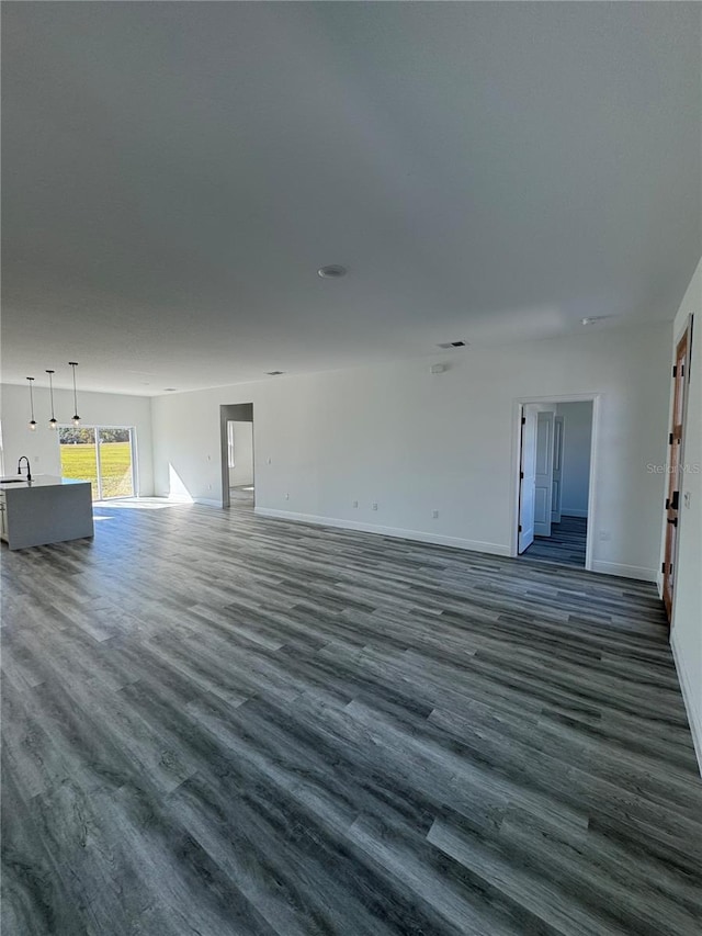 unfurnished living room with sink and dark hardwood / wood-style floors