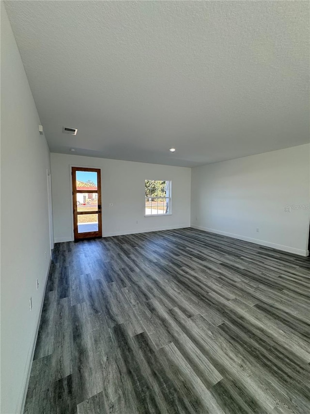 spare room featuring plenty of natural light, dark hardwood / wood-style floors, and a textured ceiling