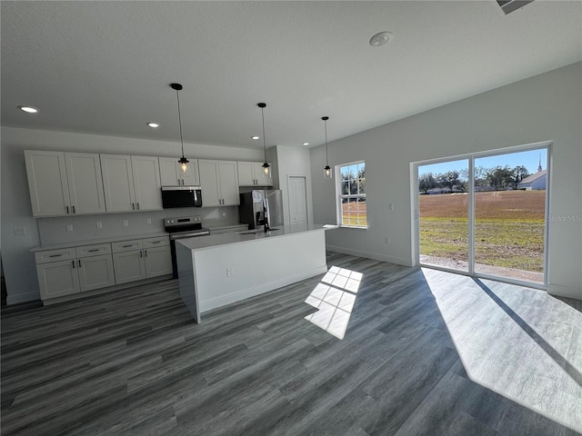 kitchen featuring hanging light fixtures, dark hardwood / wood-style floors, an island with sink, stainless steel appliances, and white cabinets