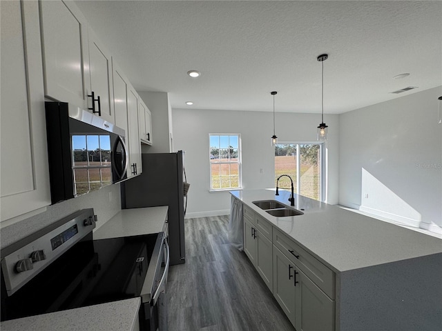 kitchen with stainless steel appliances, sink, white cabinets, and decorative light fixtures