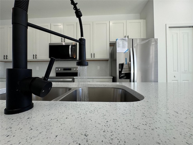 kitchen with white cabinetry, appliances with stainless steel finishes, and light stone counters